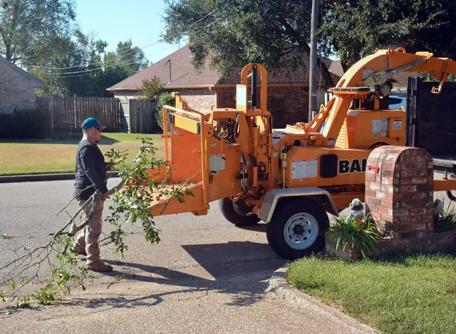 Wood chipper processing branches in a suburban neighborhood